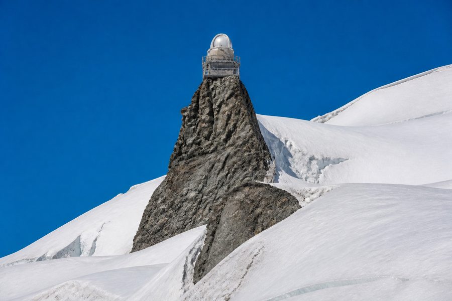 La cúpula blanca del observatorio de la Esfinge sobre un espolón de roca rodeado de nieve