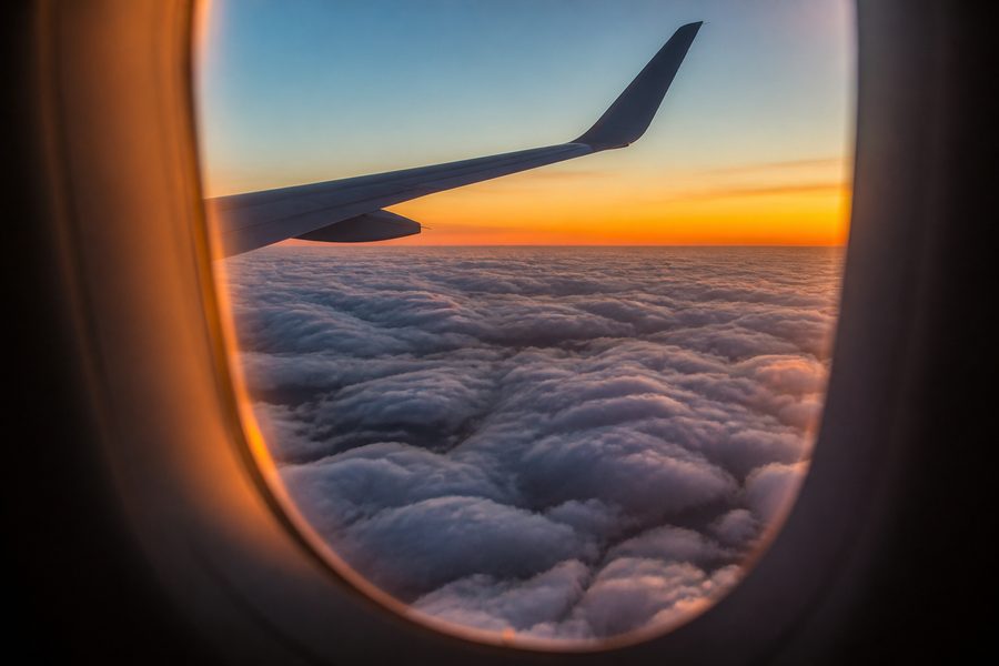Vista desde la ventanilla de un avion sobre un mar de nubes al atardecer