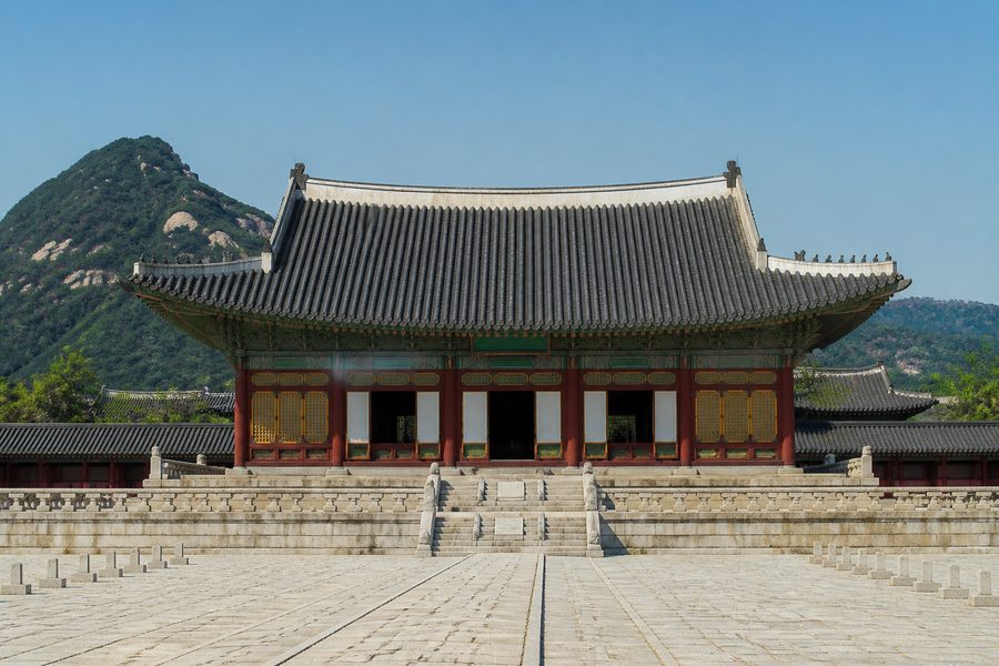 El pabellón Geunjeongjeon del palacio Gyeongbokgung, con su tejado curvo de tejas y columnas rojas, y montañas al fondo