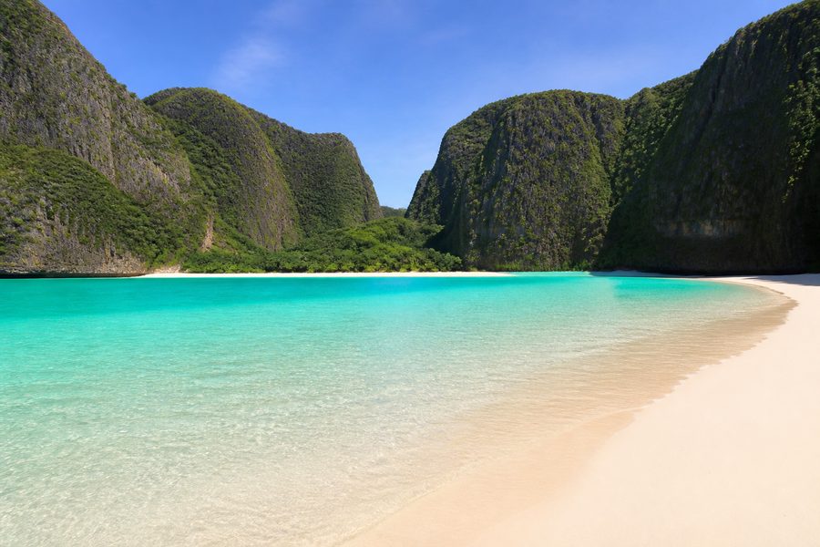 La playa de arena blanca de Maya Bay cerrada por paredes verticales de roca caliza, con el agua turquesa vacía de barcas